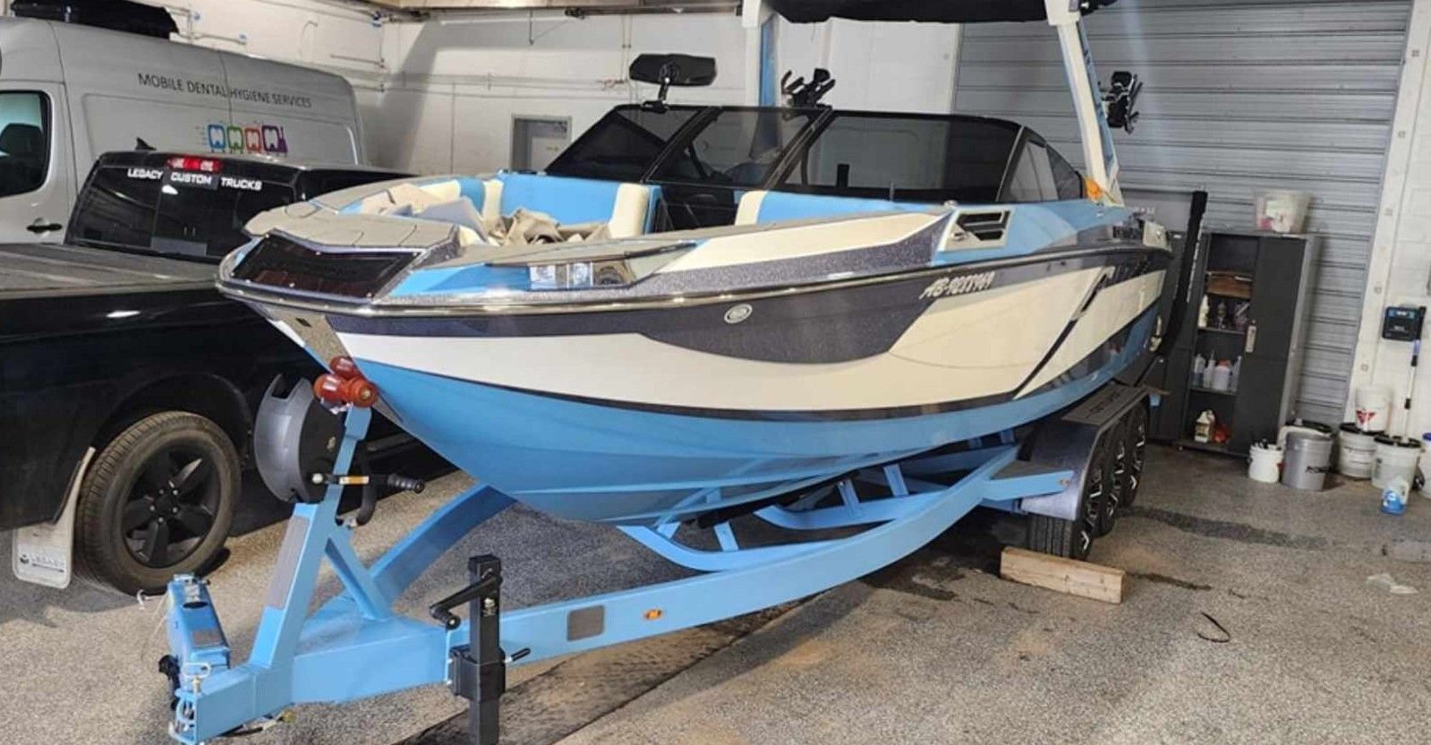 Blue and white motorboat on a blue trailer in a garage.