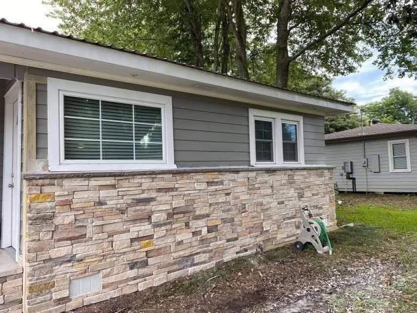 A house with a stone wall and a ladder in front of it.