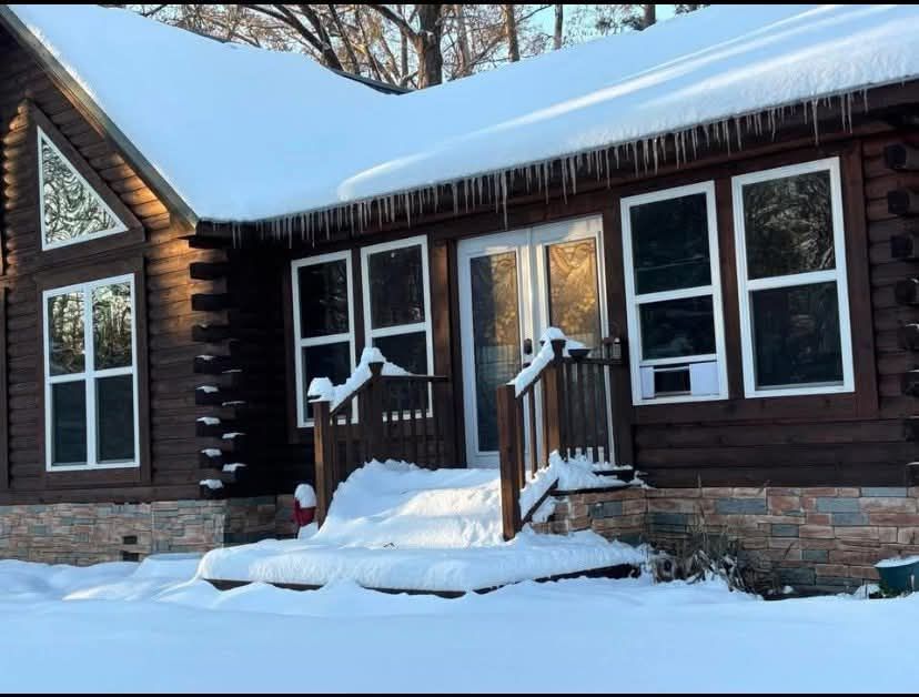 A log cabin covered in snow with icicles on the roof