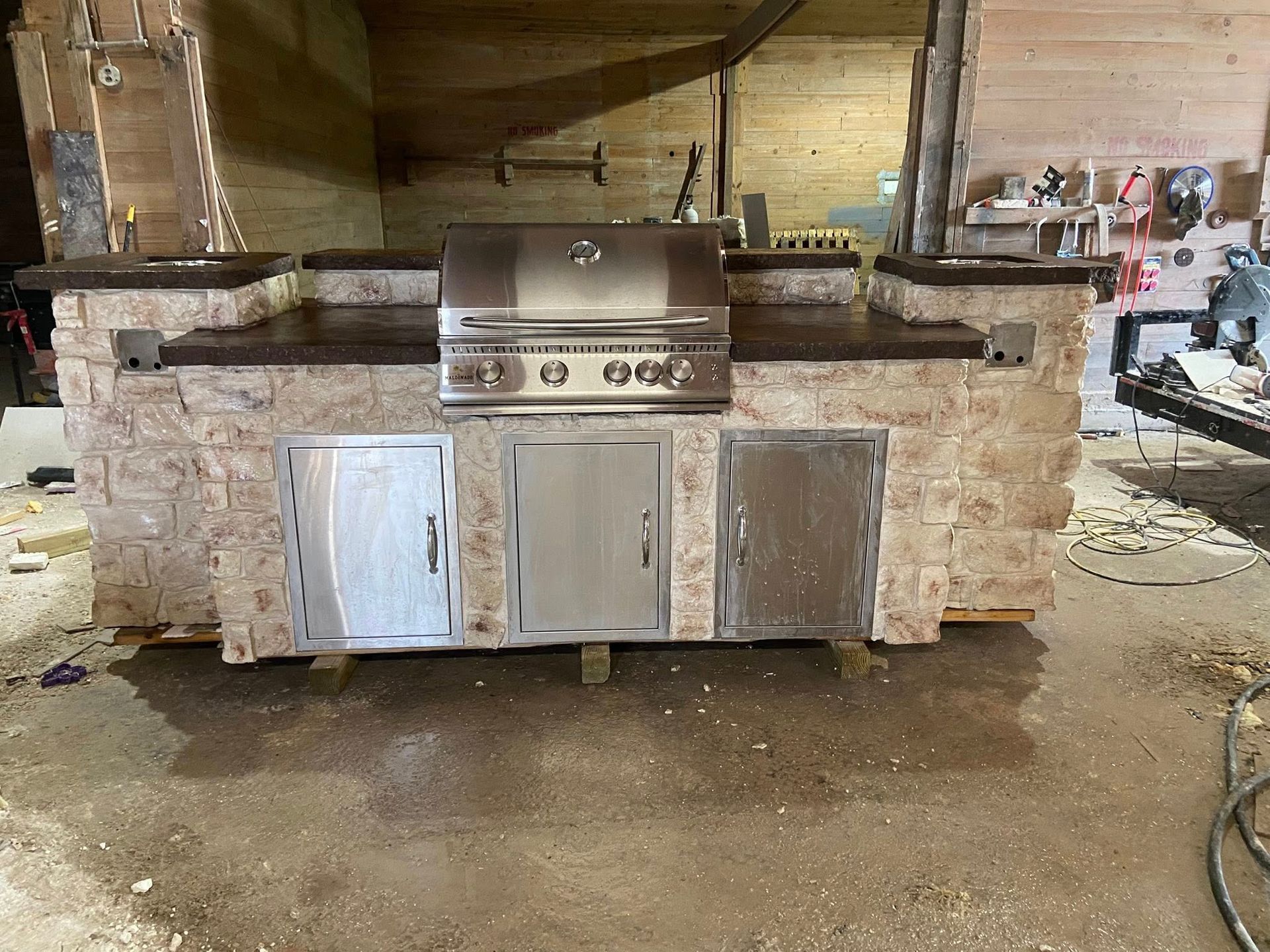 A stainless steel grill is sitting on top of a stone counter in a kitchen.