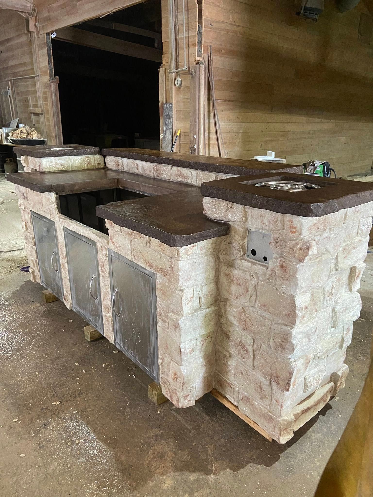 A large brick kitchen island is sitting on top of a wooden table.