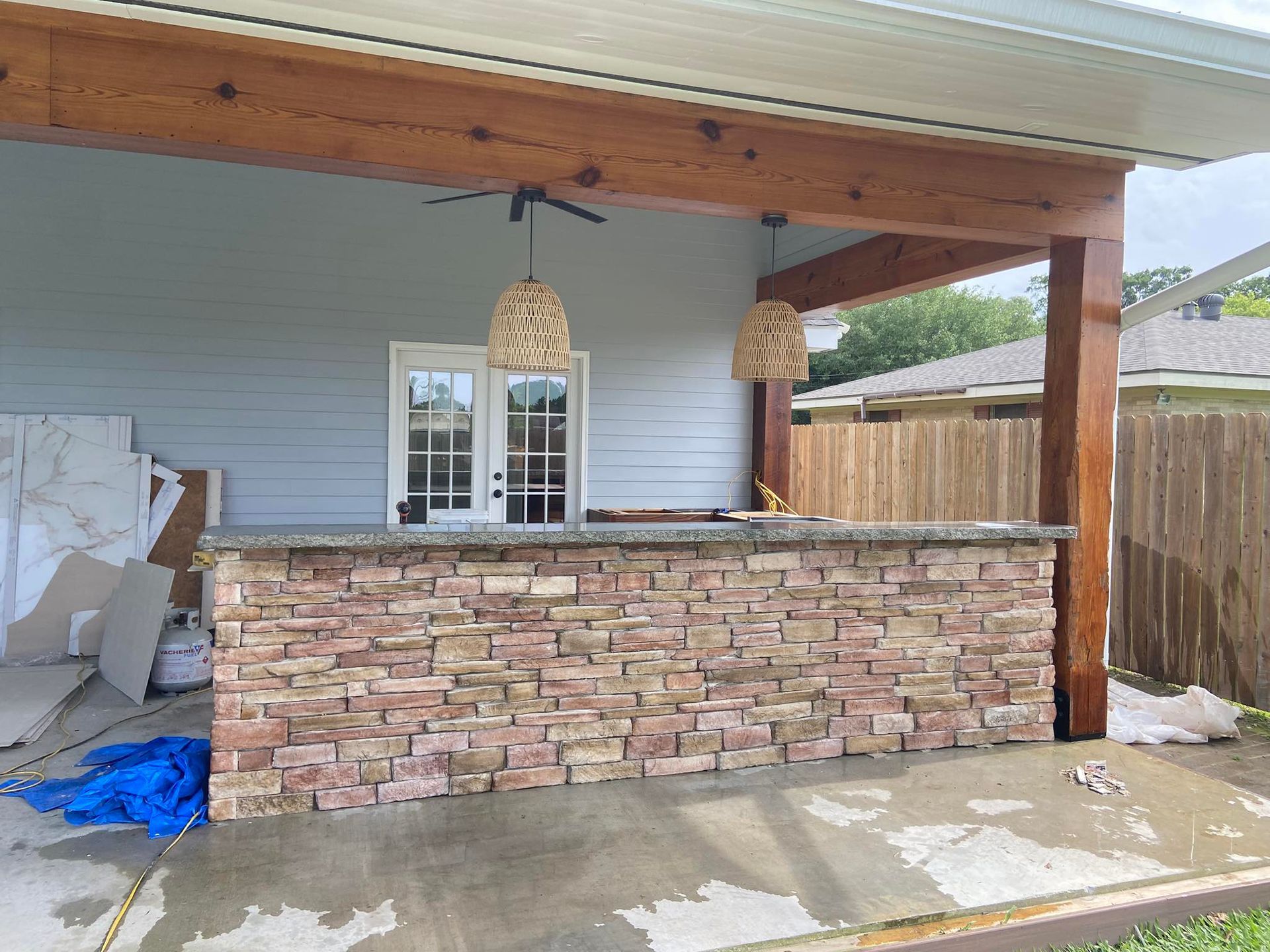A patio with a stone bar and a ceiling fan.