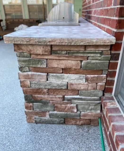 A brick wall with a green hose attached to it