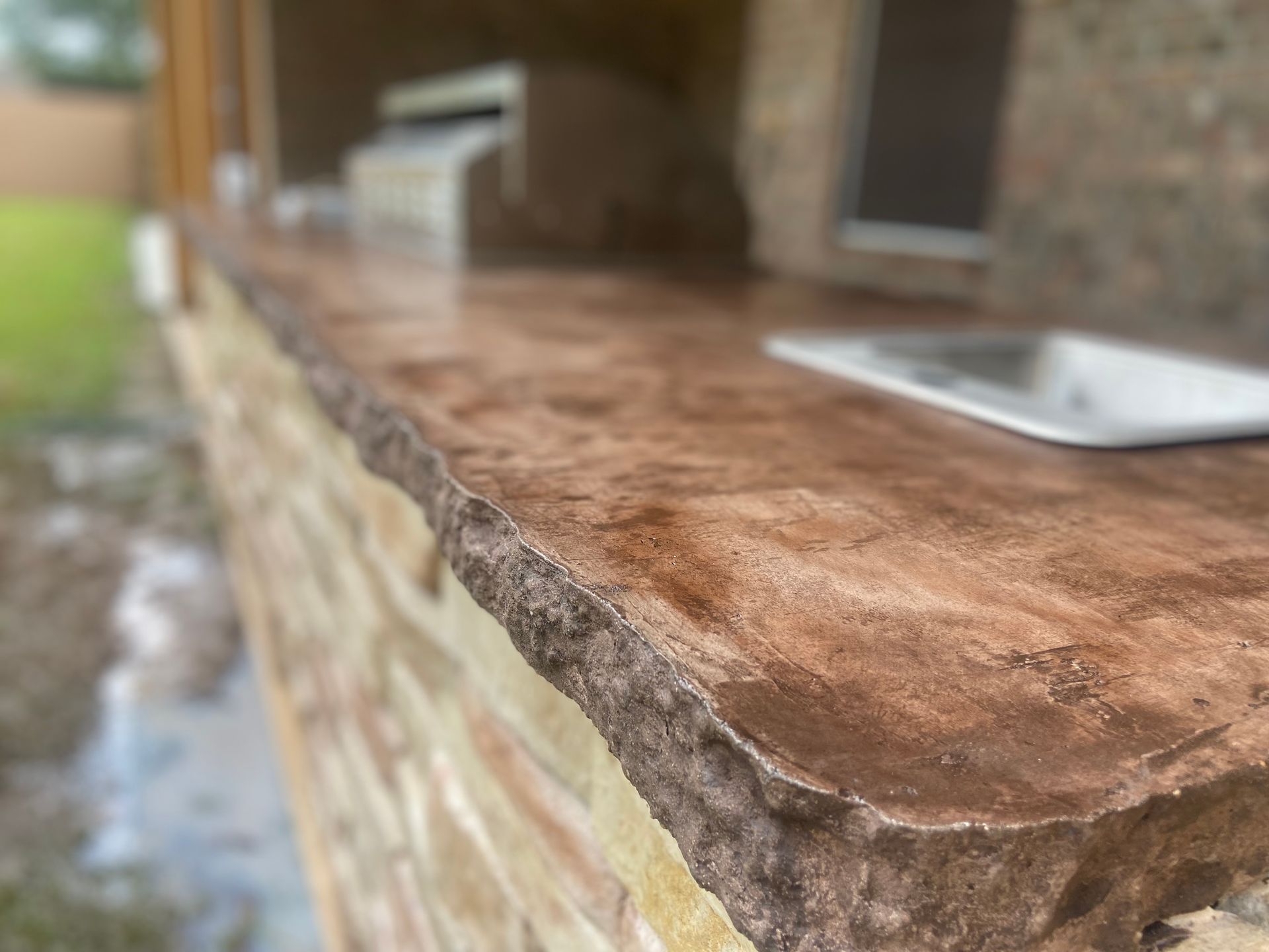 A close up of a concrete counter top on a brick wall.