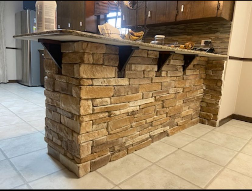 A kitchen with a brick wall and a marble counter top.