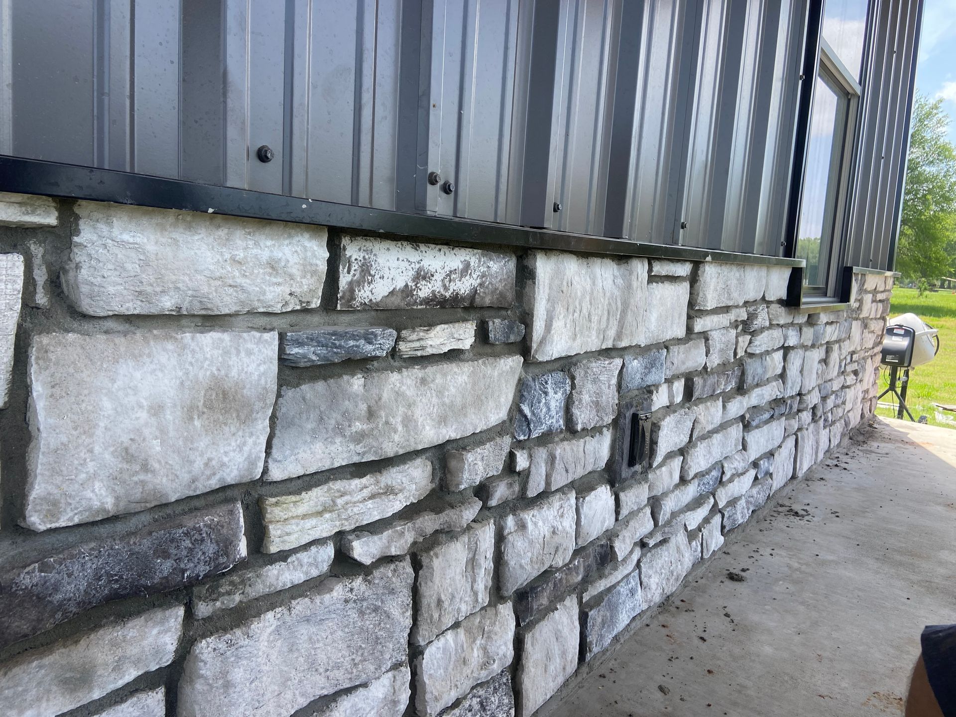 A stone wall with a metal siding on the side of a building.