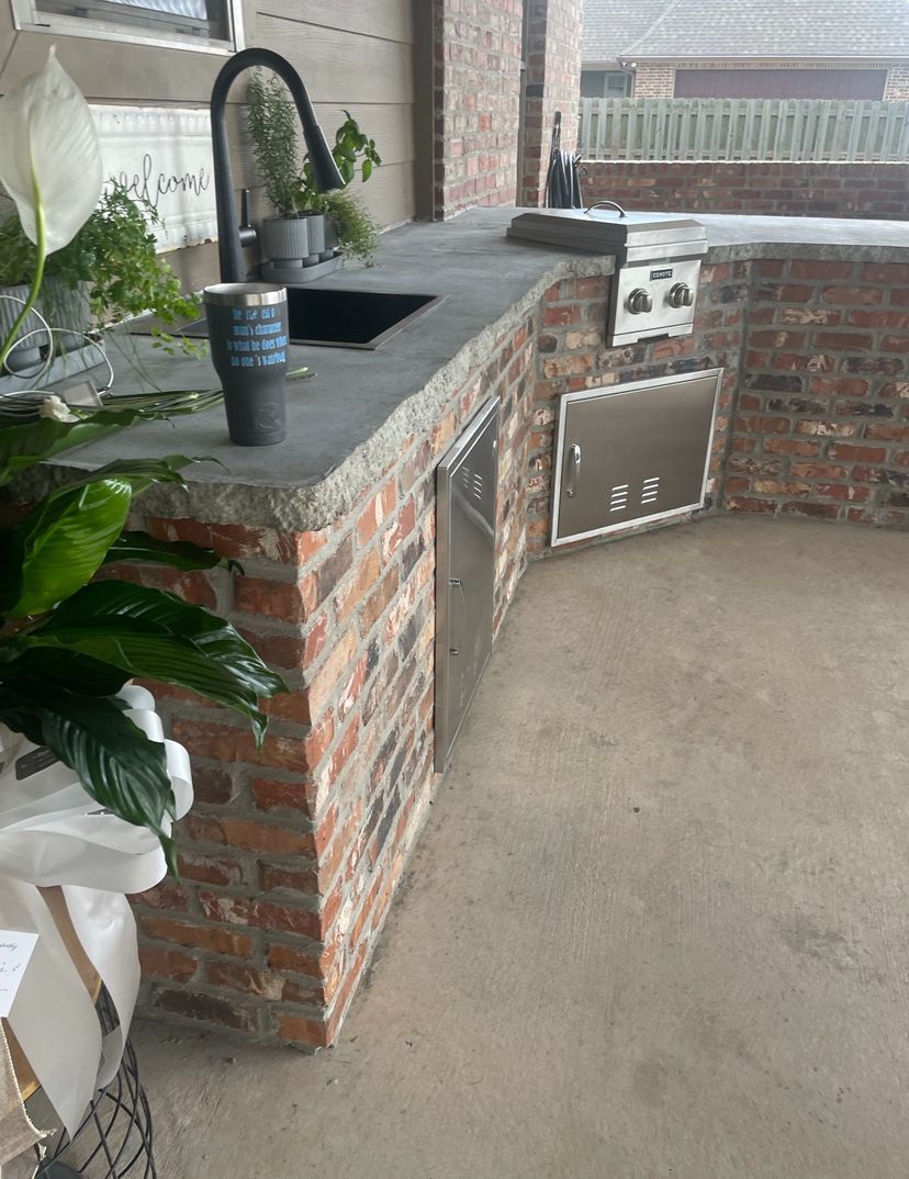 A brick kitchen with a sink , stove , and potted plant.