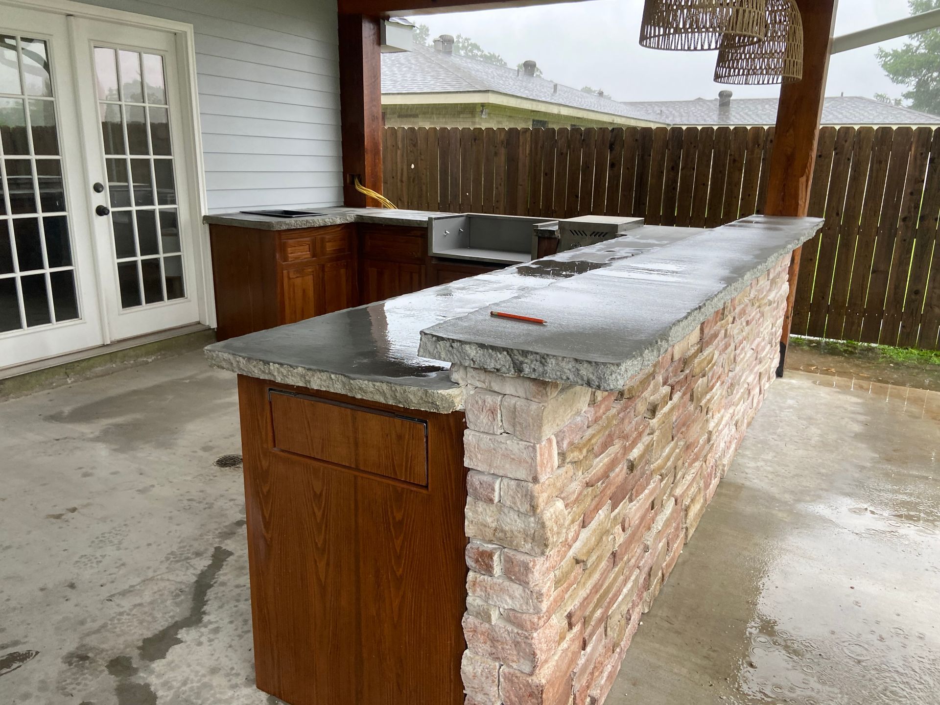 A kitchen with a brick counter top and a stainless steel sink.
