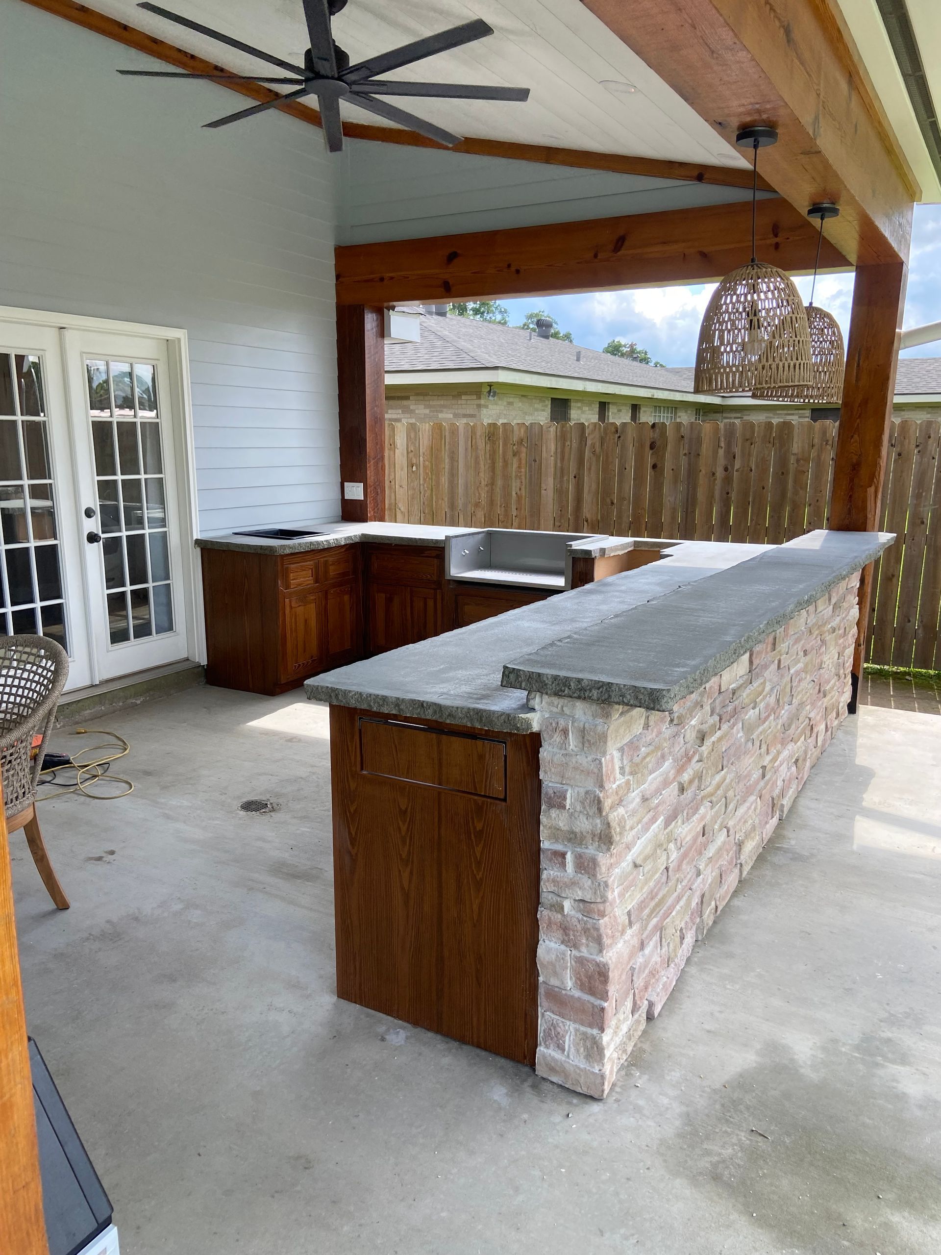A patio with a brick bar and a ceiling fan