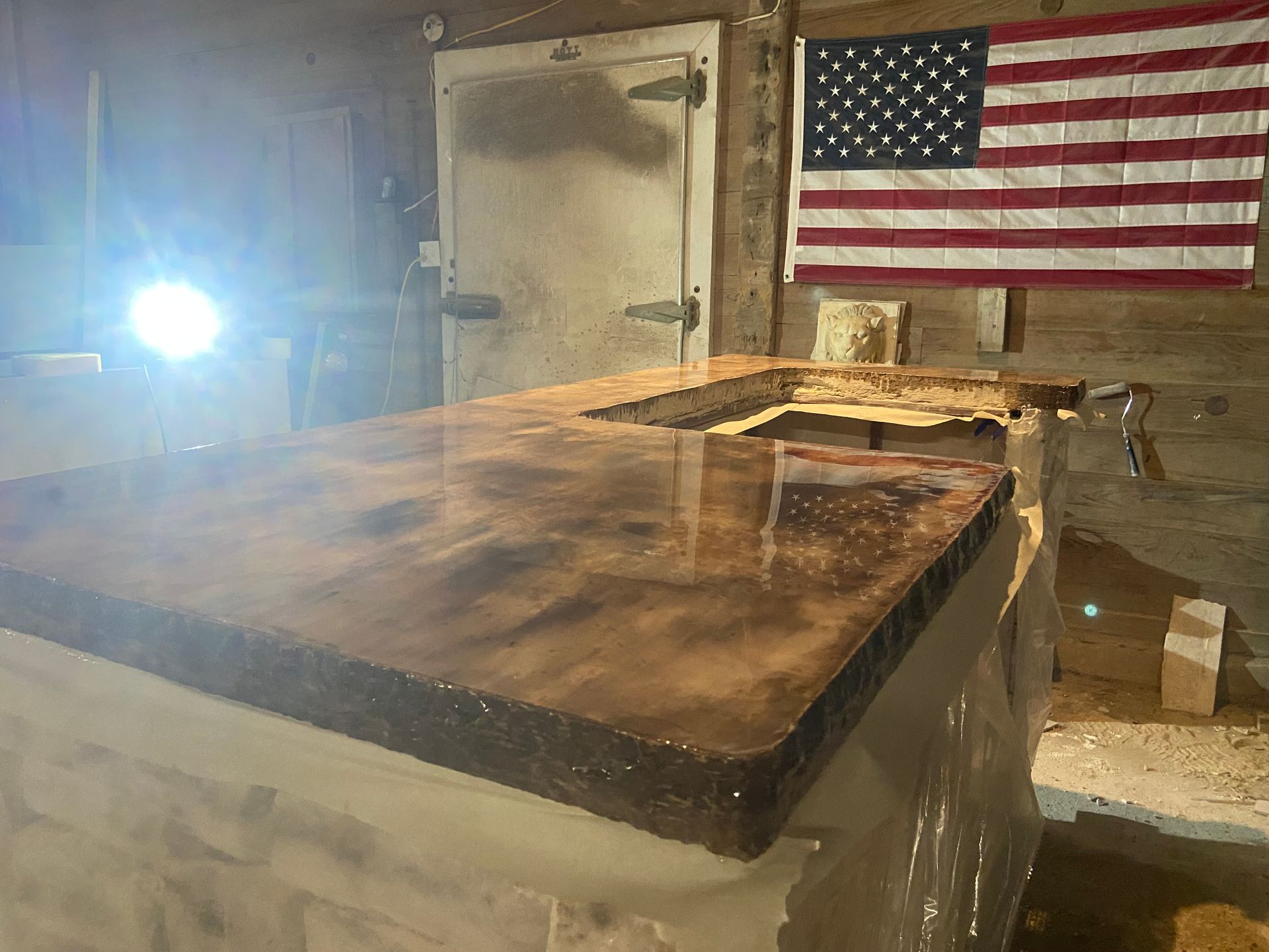 A kitchen counter with an american flag hanging on the wall.
