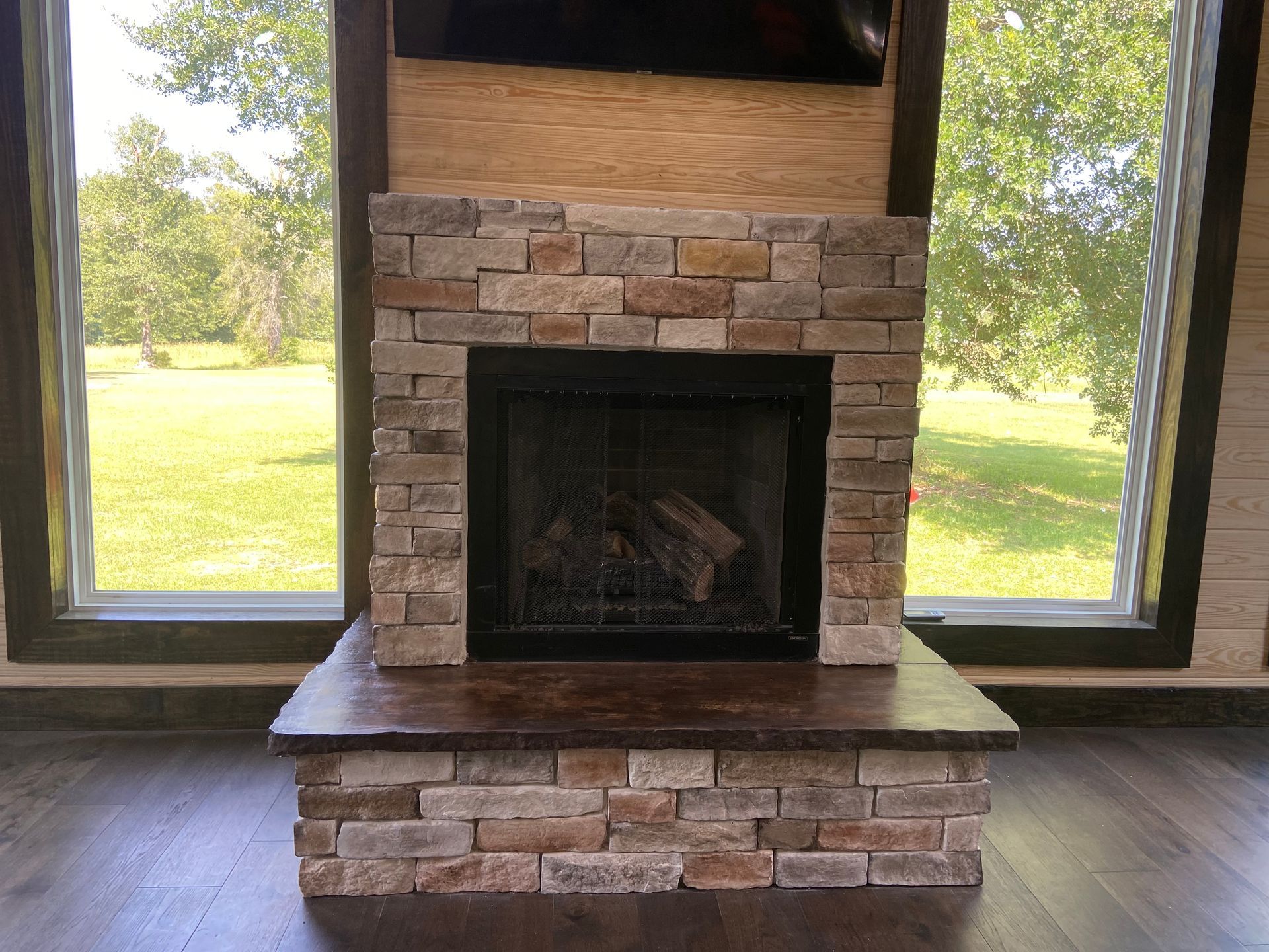 A fireplace in a living room with a large window.