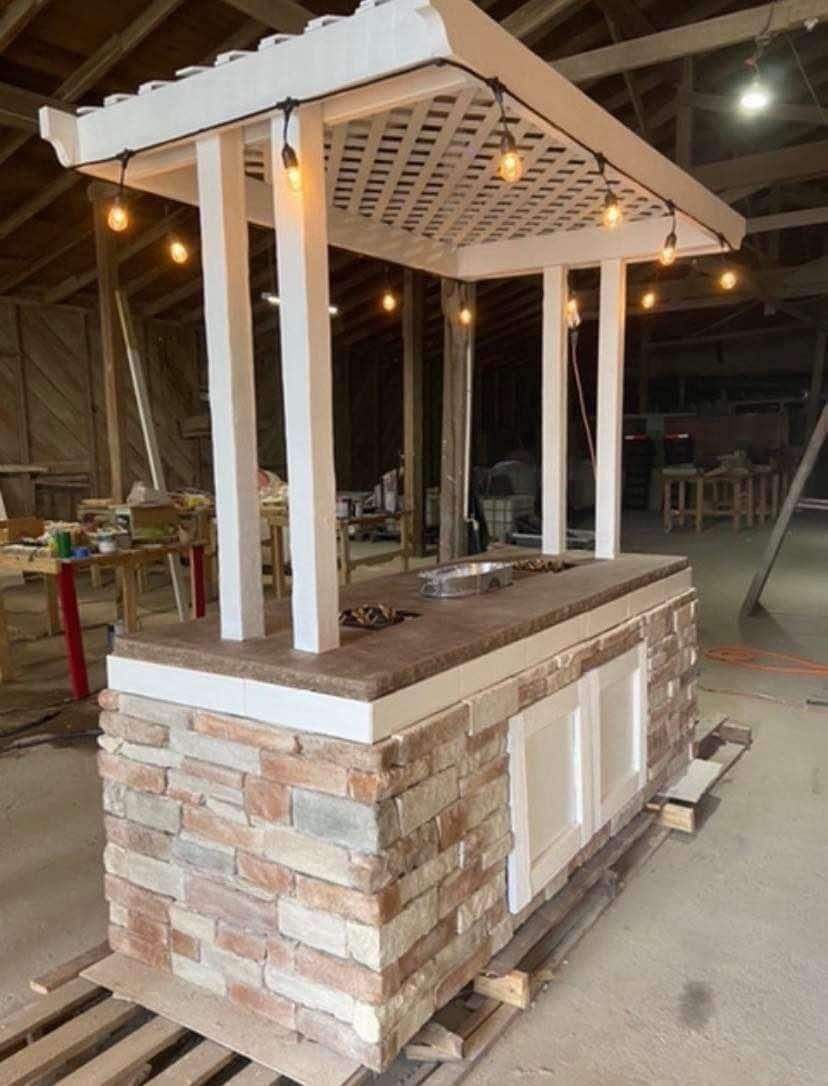A brick island with a pergola and lights sitting on top of a wooden pallet.