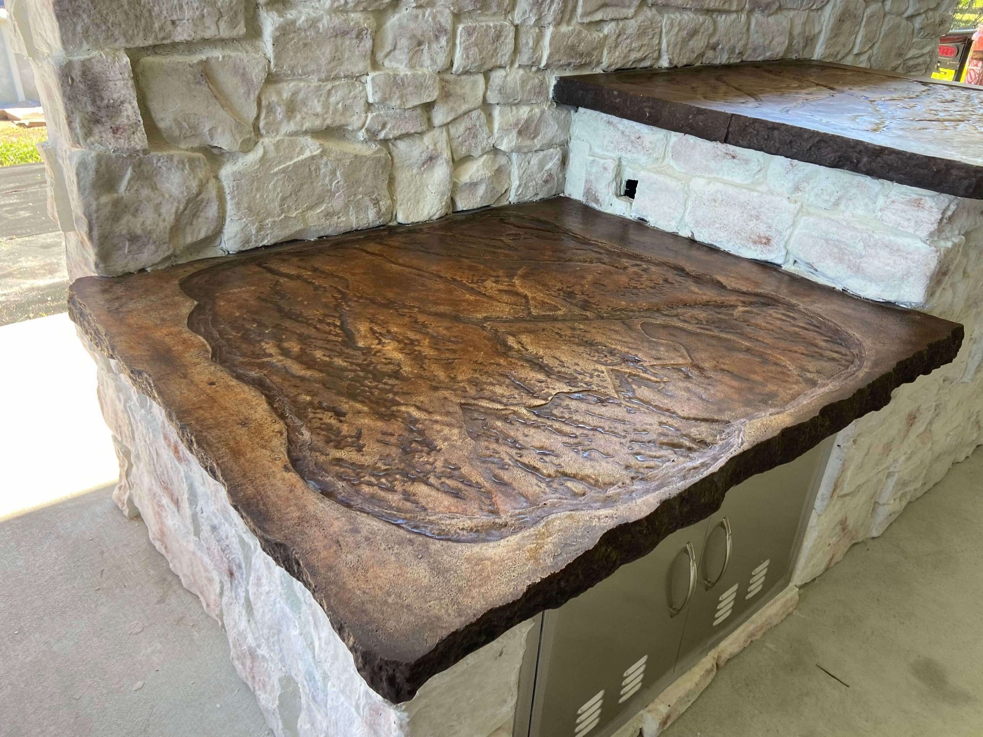 A concrete counter top with a stone wall in the background.