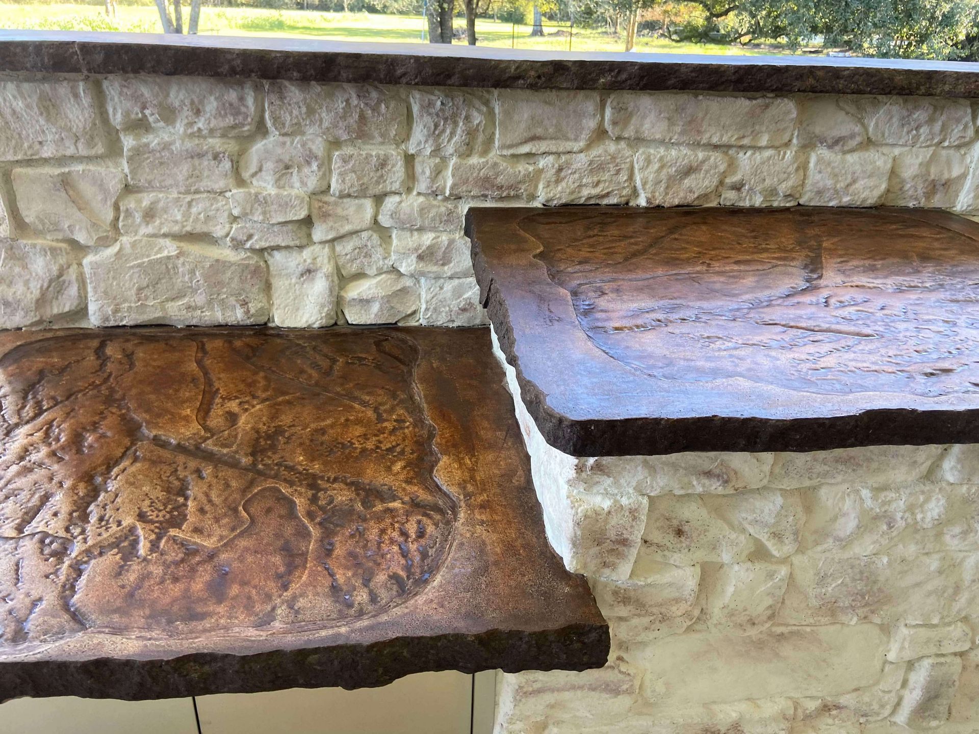 A concrete counter top with a stone wall in the background.