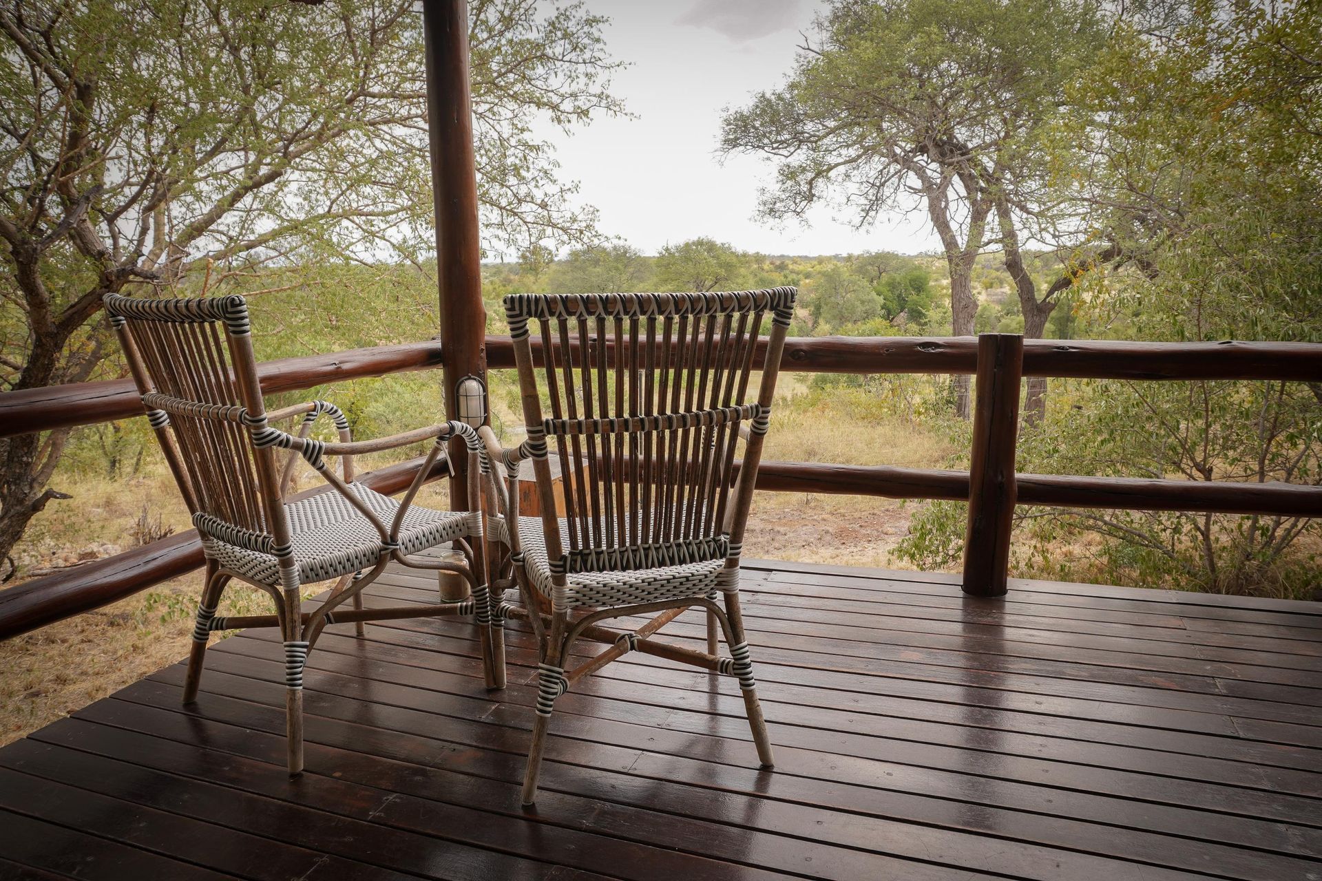 Two chairs are sitting on a wooden deck overlooking a field.