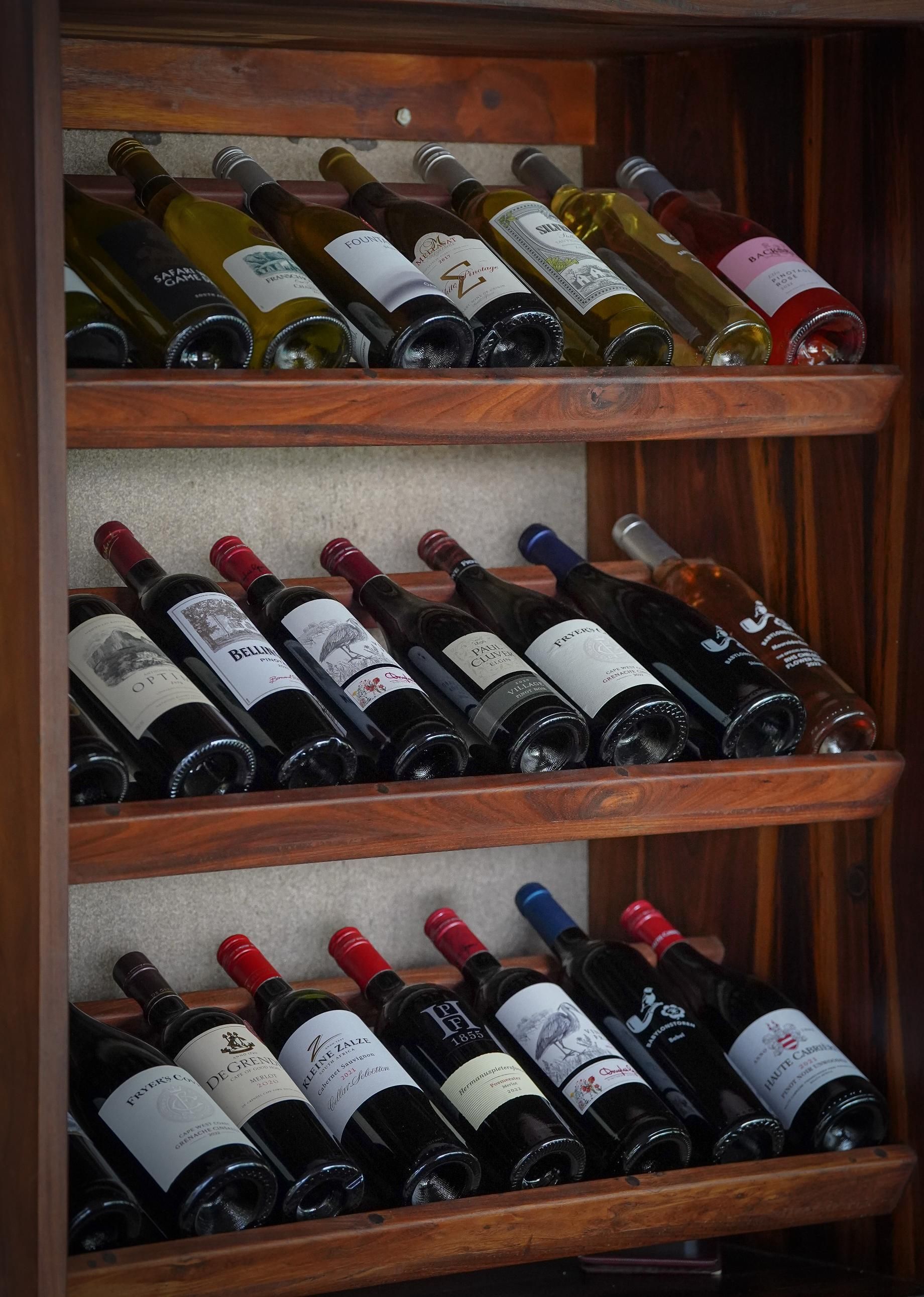 Bottles of wine are lined up on wooden shelves