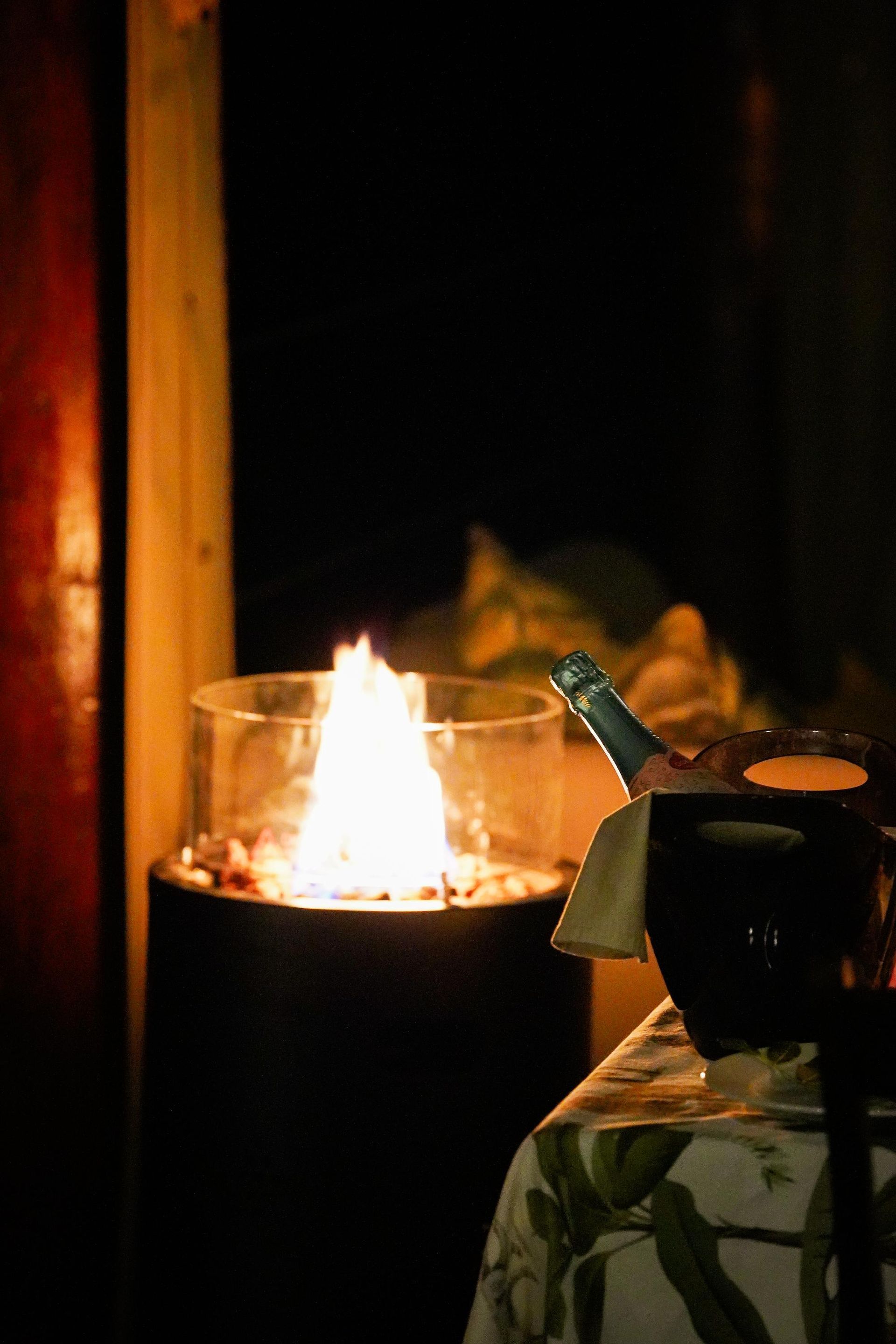 A bottle of champagne is sitting on a table next to a fire pit.