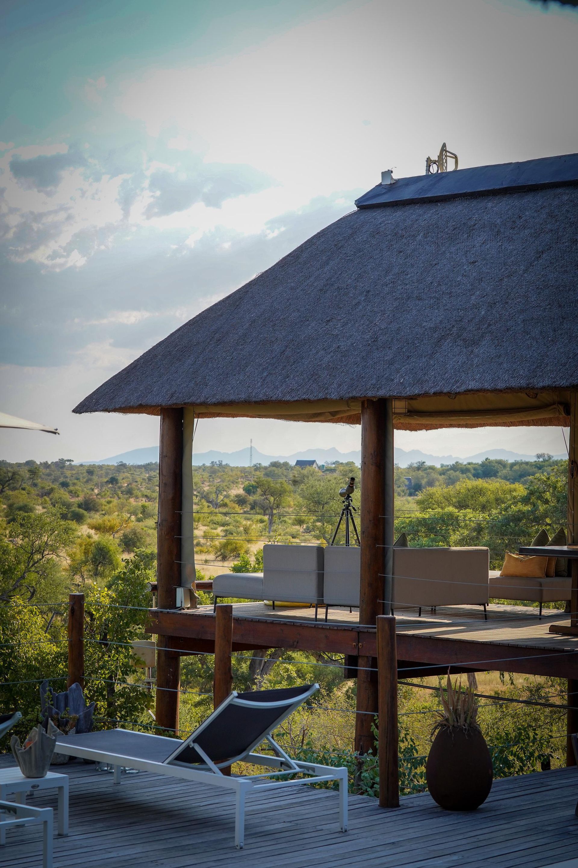 A gazebo with a thatched roof and lounge chairs