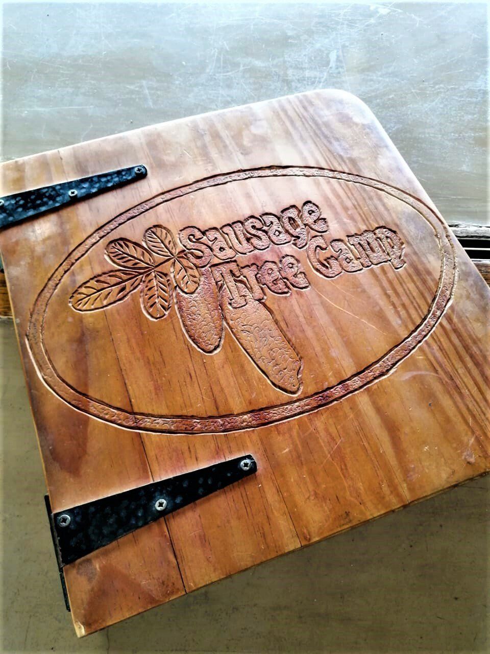 A wooden sign with the word sausage on it is sitting on a table.