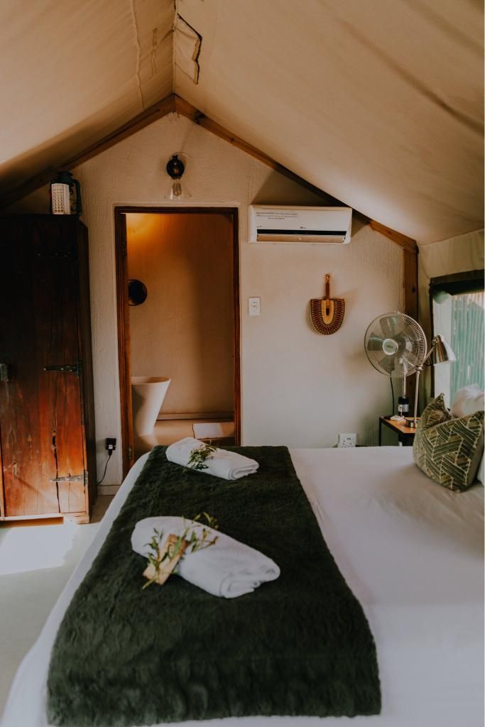 A bedroom with a bed , a fan and a toilet.
