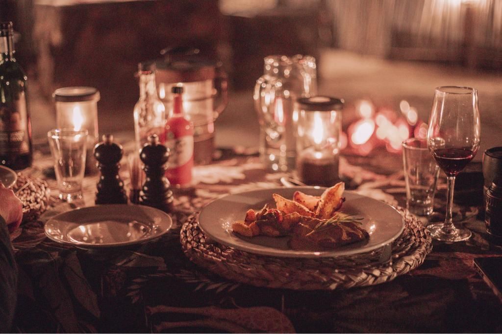 A table with plates of food and wine glasses on it.