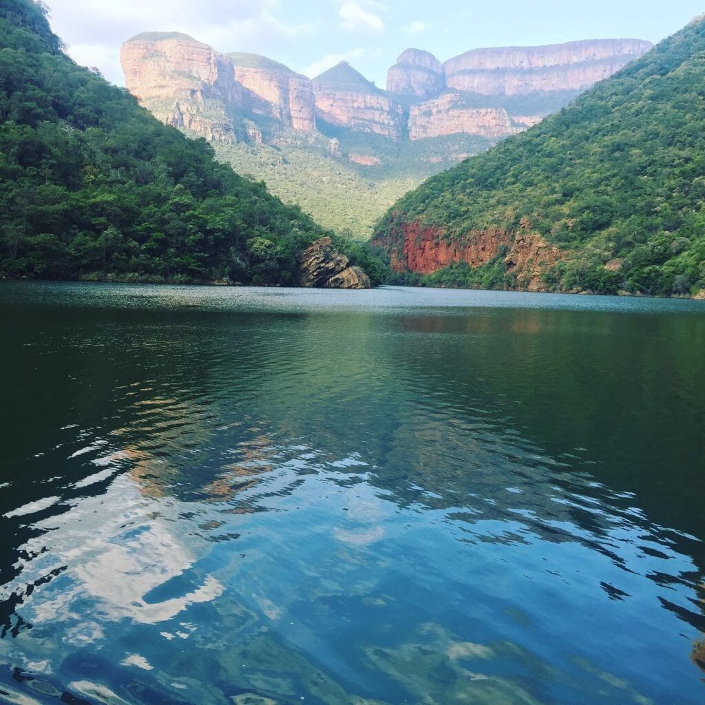 A lake surrounded by mountains and trees with mountains in the background