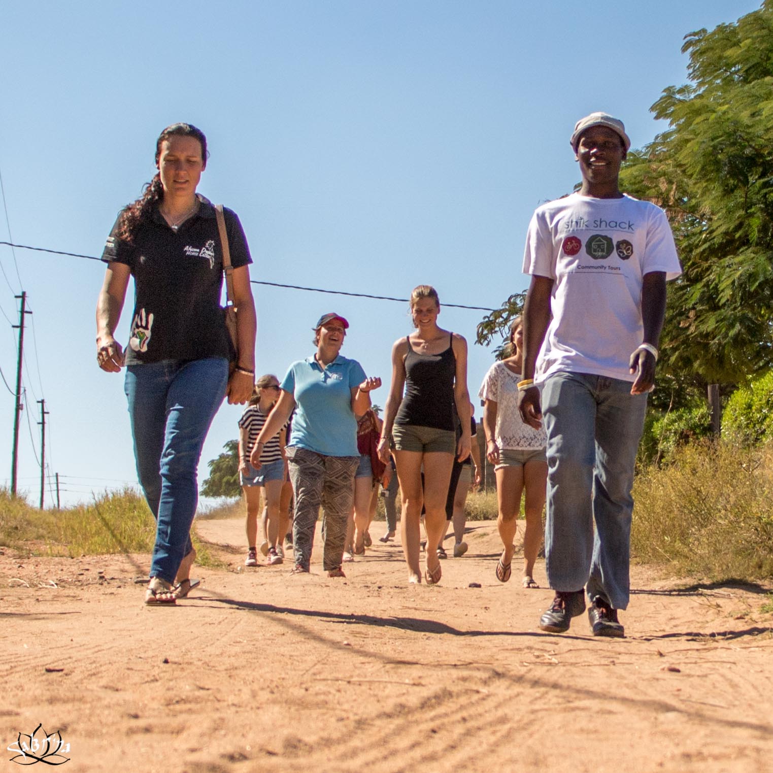 a group of people are walking down a dirt road and one of them is wearing a shirt that says life shock
