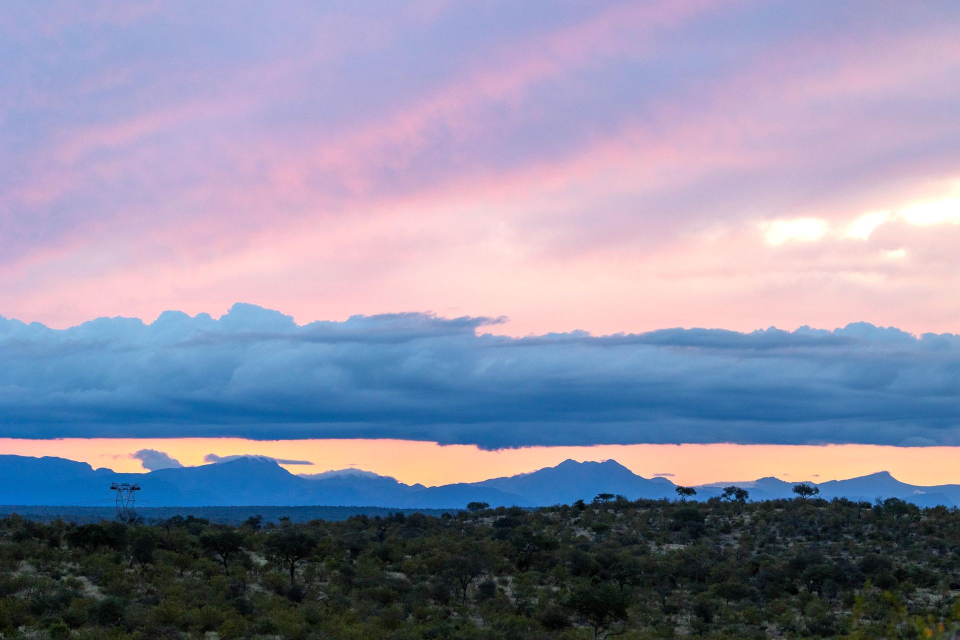 A sunset over a mountain range with trees in the foreground