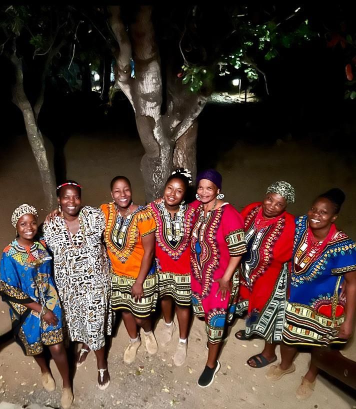a group of women posing for a picture in front of a tree