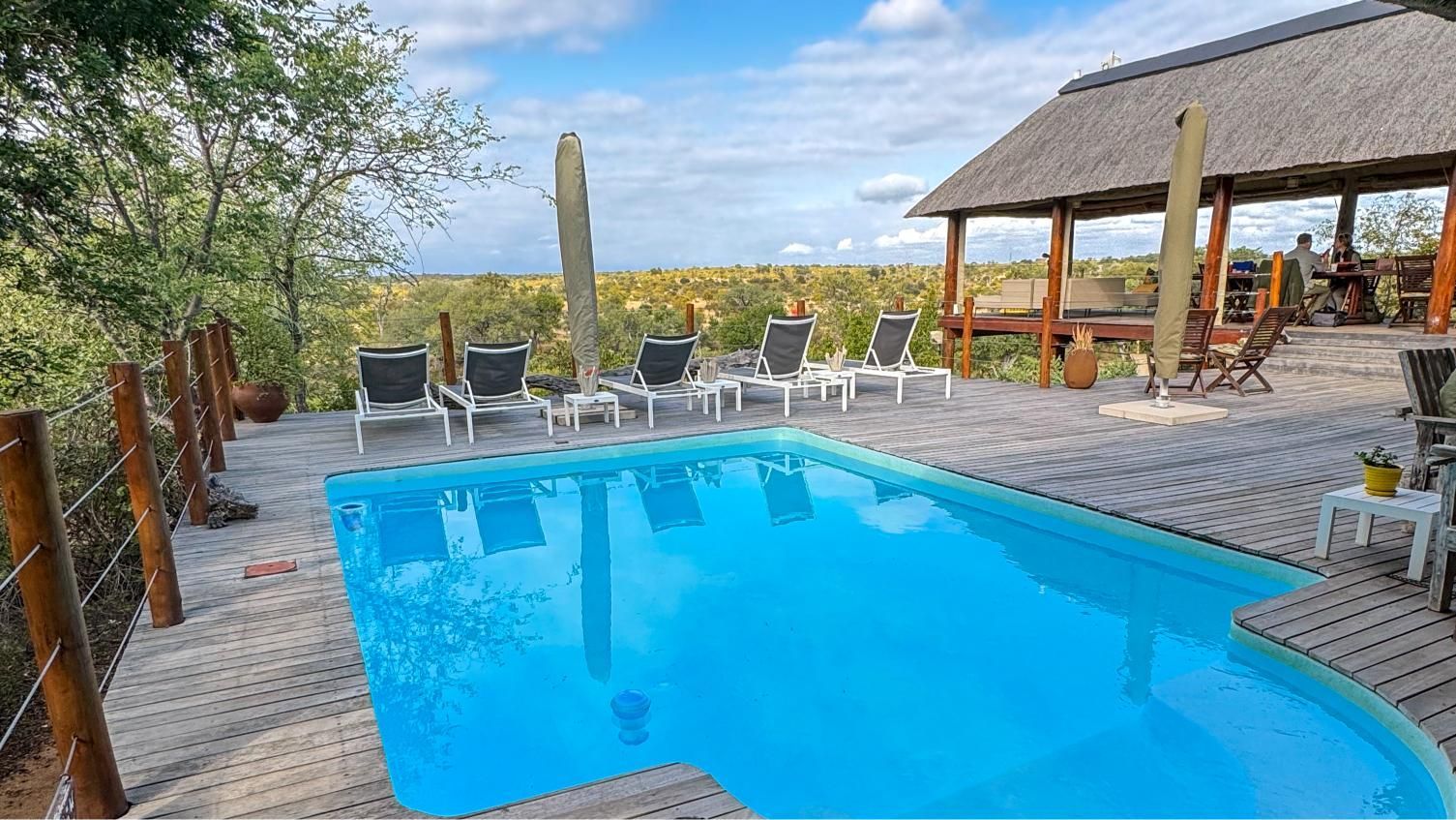 A large swimming pool with chairs and umbrellas around it.