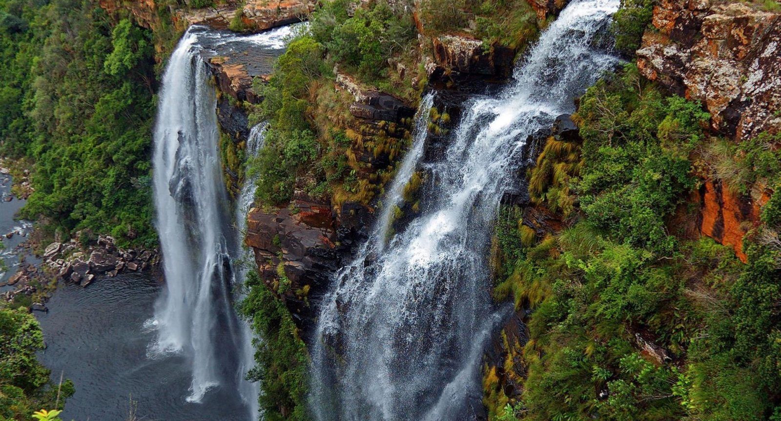 A waterfall is surrounded by trees and rocks in the middle of a forest.