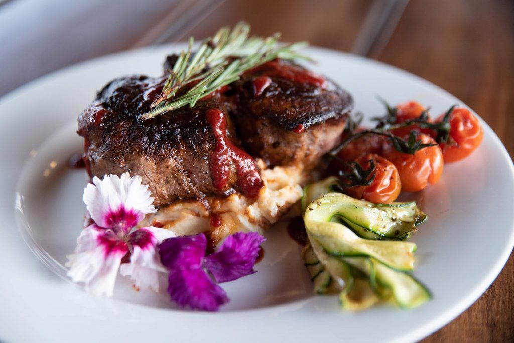 A white plate topped with a piece of meat and vegetables.