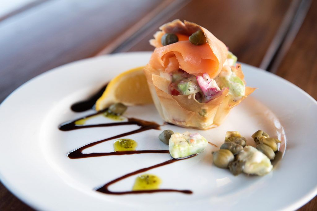 a white plate topped with a salad and smoked salmon