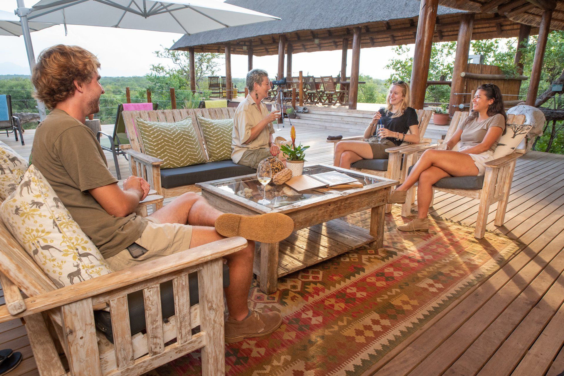 a group of people are sitting on a deck drinking wine