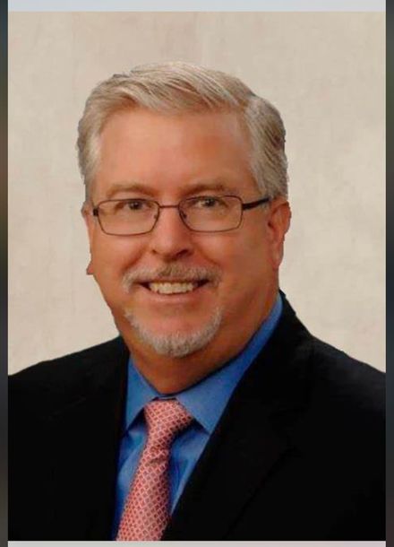 A man in a suit and tie is smiling for the camera