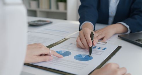 A woman is pointing at a pie chart on a clipboard.