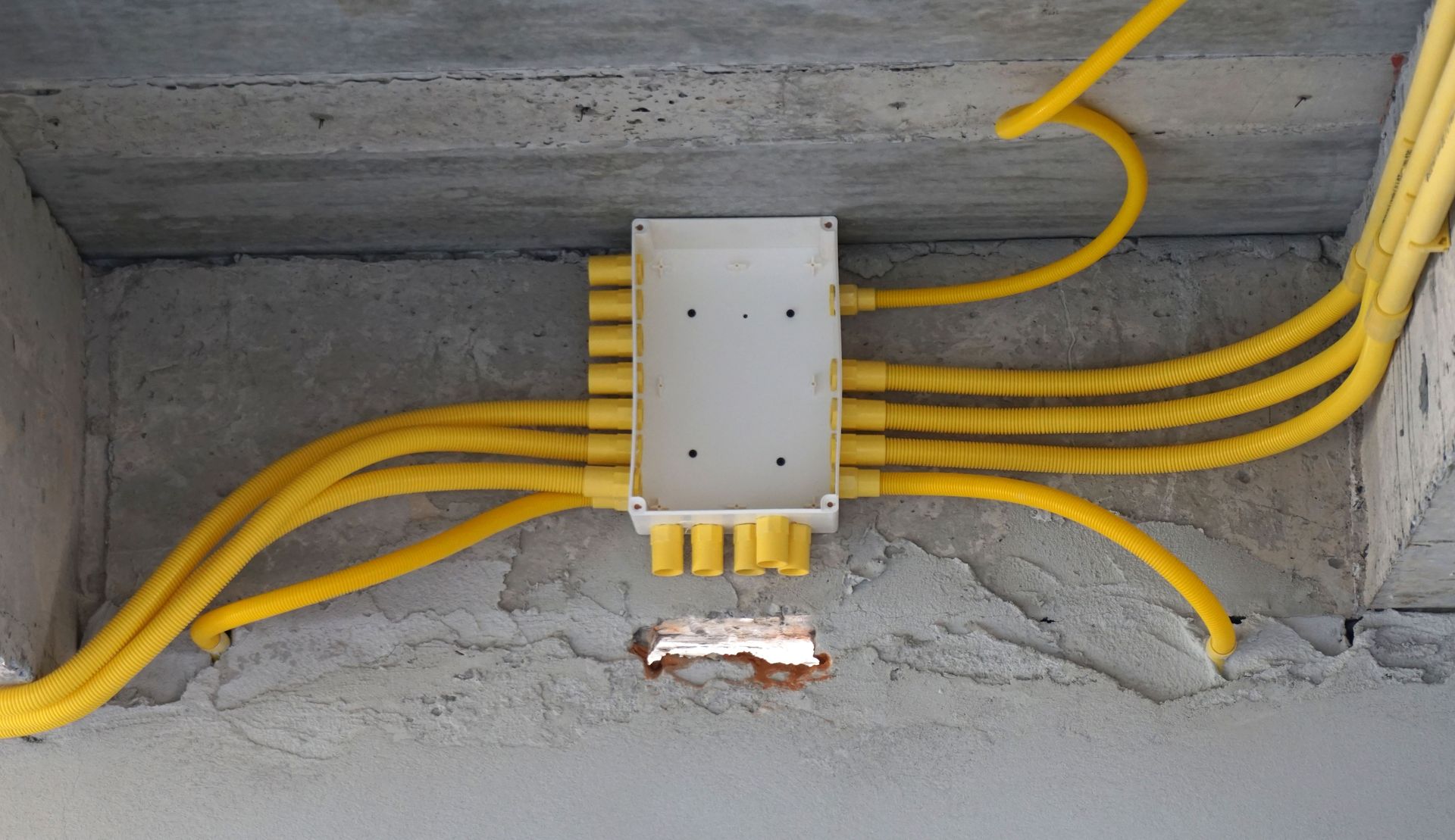 A bunch of yellow wires are connected to a box on the wall.