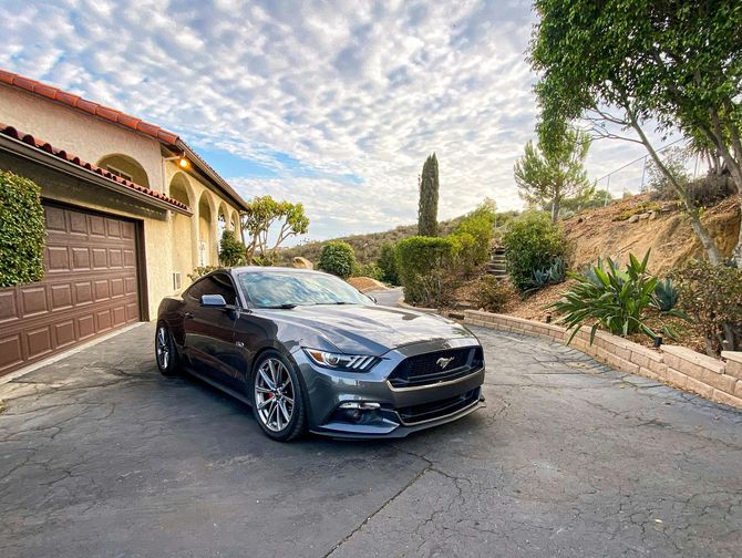A black car is parked in front of a red barn