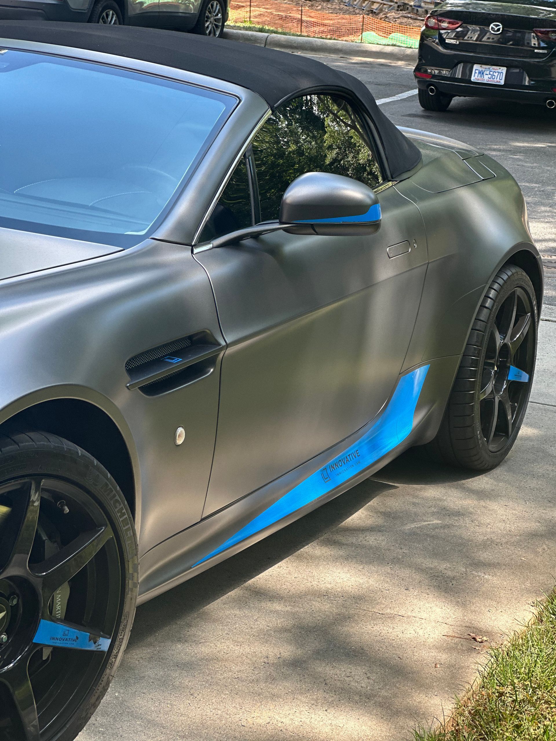 A silver sports car with a black top is parked on the side of the road.