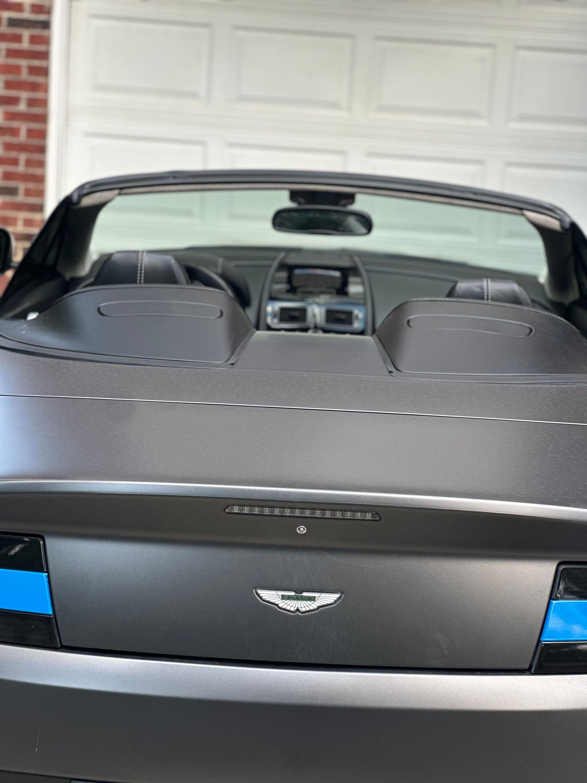 A black convertible is parked in front of a garage door.