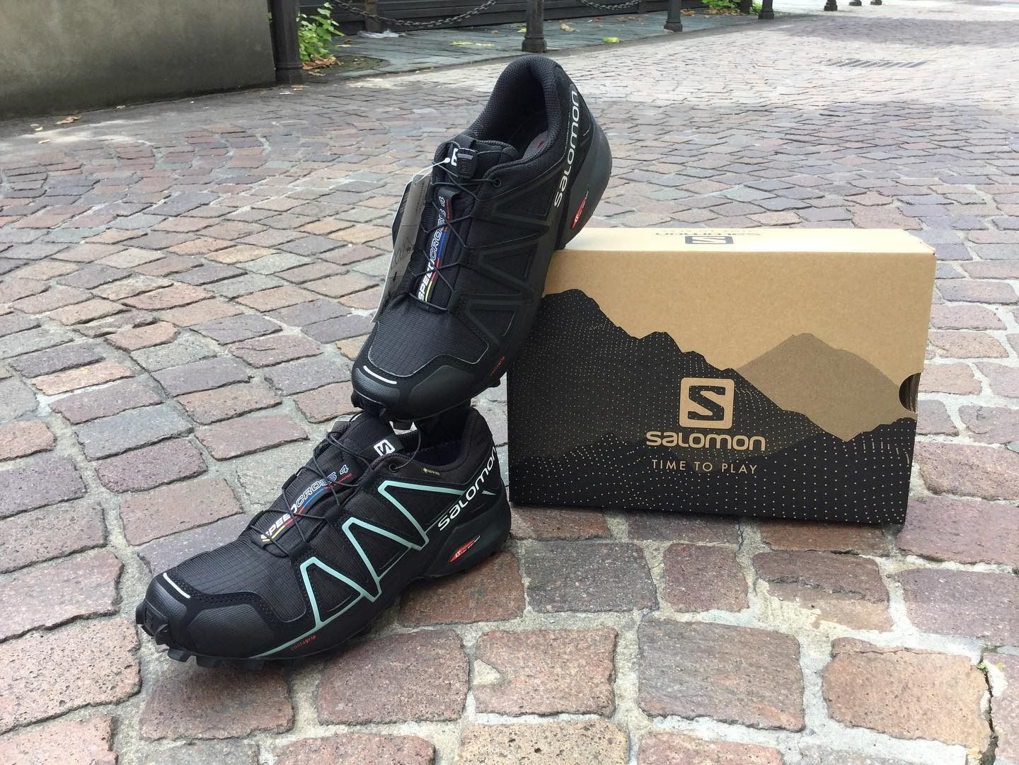 Scarpe da trail running Salomon nere e box su ciottoli.