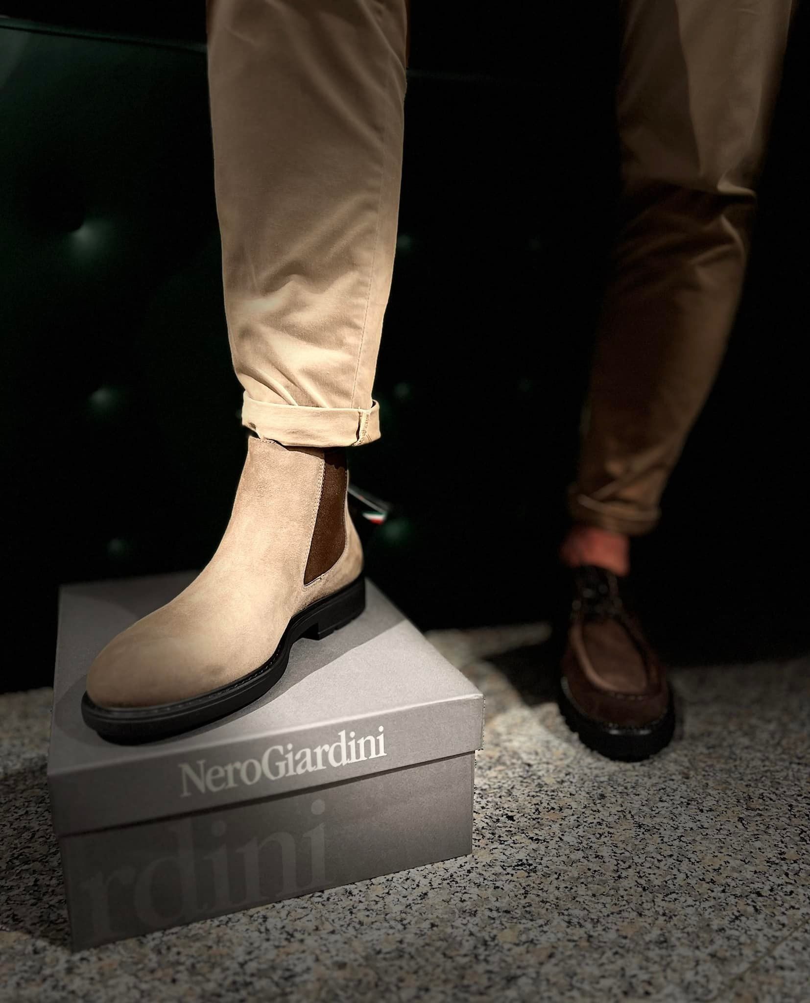 Persona che indossa pantaloni color cuoio e stivali Chelsea scamosciati marrone chiaro