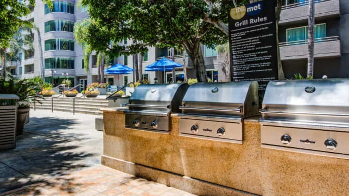 a row of grills are sitting on a sidewalk in front of a building .