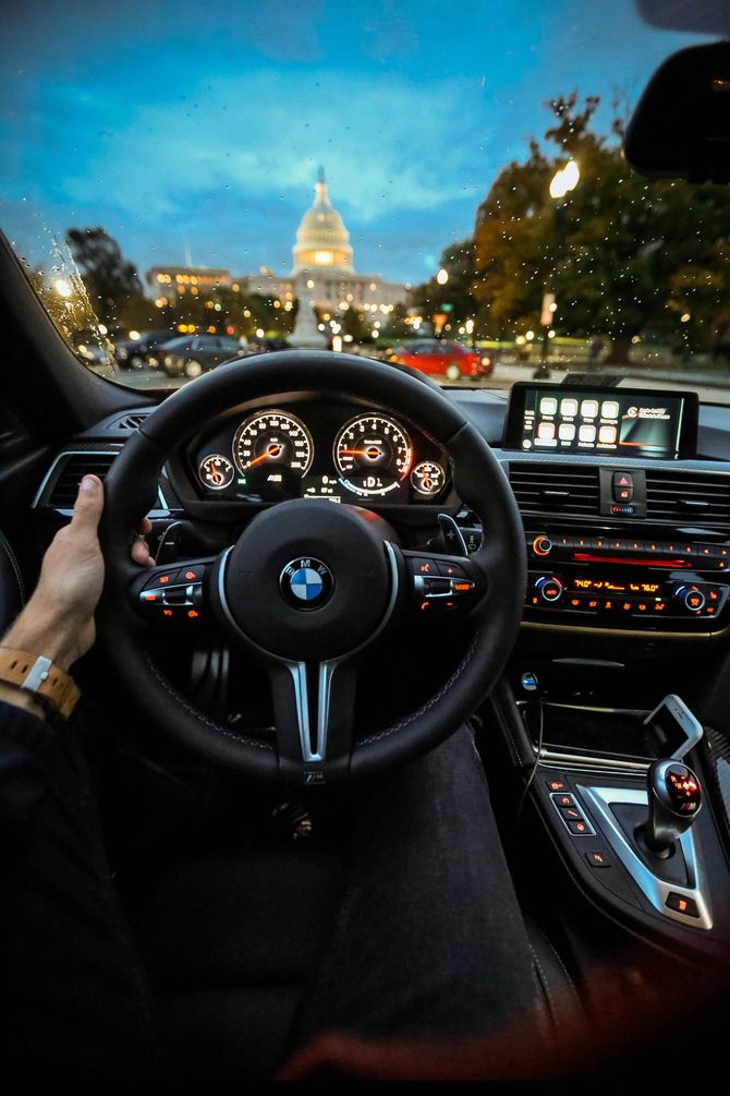 A person is holding the steering wheel of a bmw car.