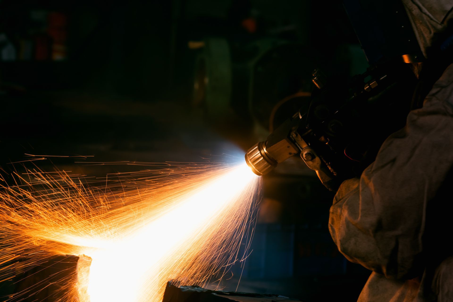 A man wearing a helmet and gloves is sandblasting a turbine.