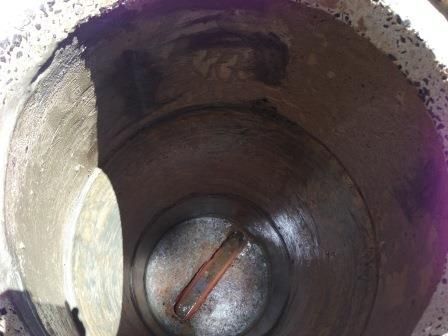 A close up of the inside of a metal container with purple liquid coming out of it.
