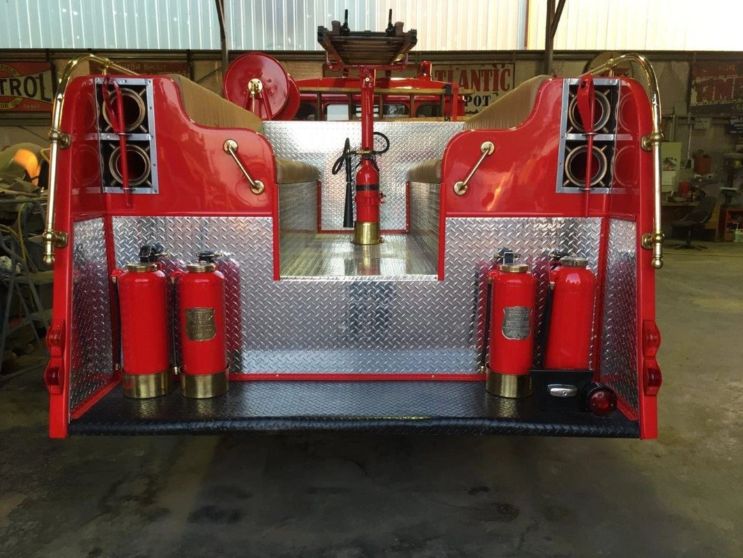 A red fire truck with fire extinguishers on the back is parked in a garage.