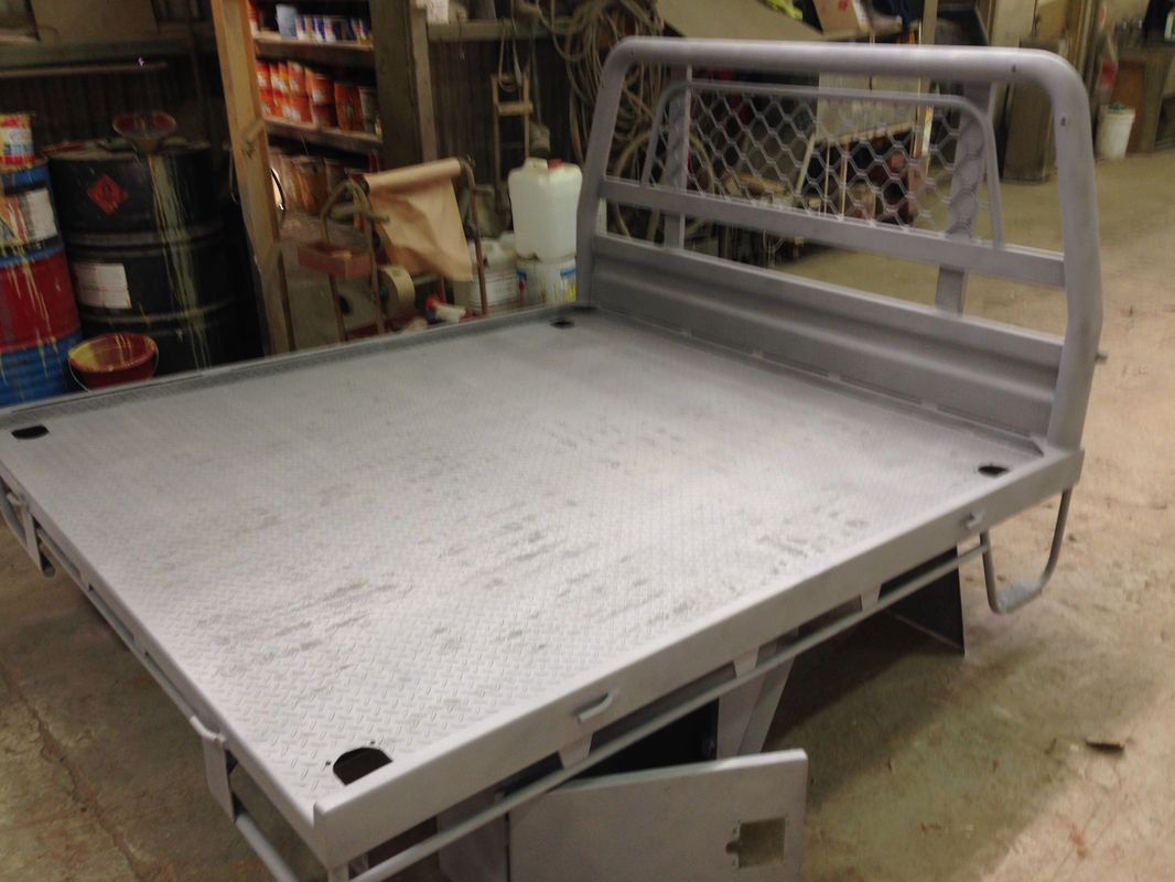 A truck bed is sitting on the floor in a garage.
