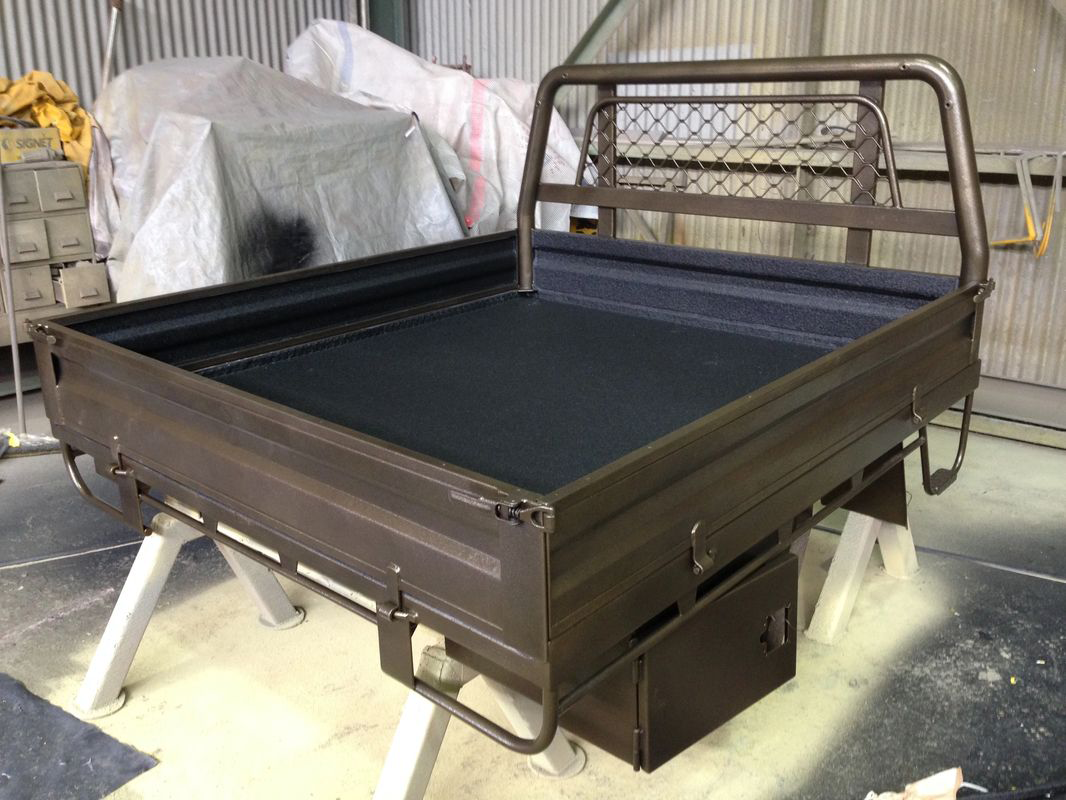 A truck bed is sitting on a table in a garage.