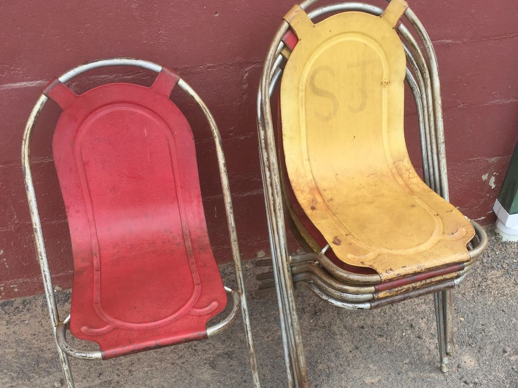 Two red and yellow chairs are stacked on top of each other in front of a red wall.